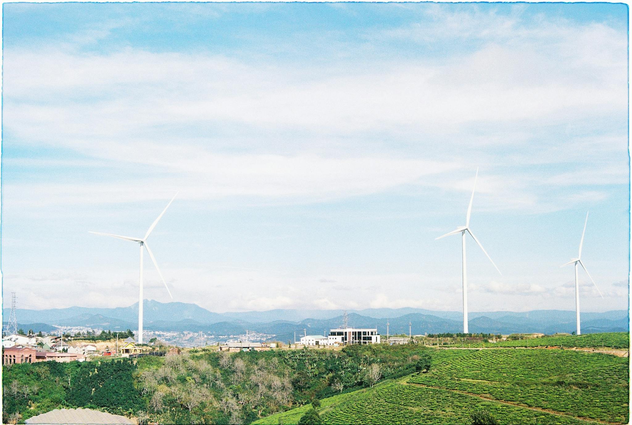 Aerial view of wind turbines set amidst the lush rural landscape of Dalat, Vietnam, showcasing renewable energy.